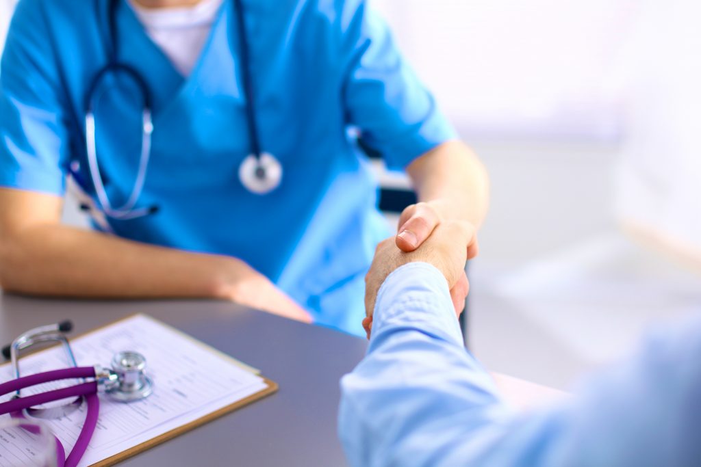 Attractive female doctor shaking a patient's hands in her office.